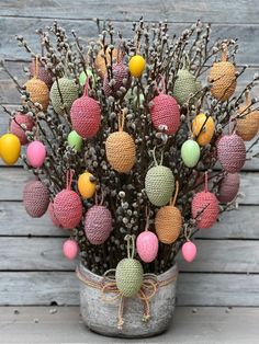 an arrangement of knitted balls and branches in a bucket on a wooden table with wood planks