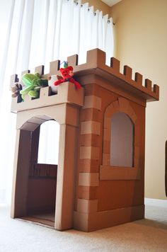 a cardboard castle made to look like it is built into the ground and has a stuffed animal on top
