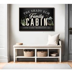 the shady elm family cabin sign hangs above a white bench with baskets on it in front of a door