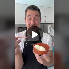 a man holding a bowl with food in it and eating something out of the bowl