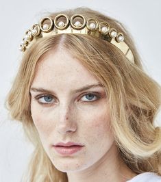 a woman with blonde hair wearing a gold tiara on her head and blue eyes