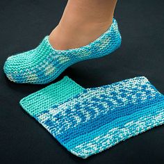 a woman's feet in blue knitted slippers on top of a black surface