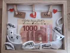 a wooden frame with money and hearts hanging on the clothes pegs in front of it