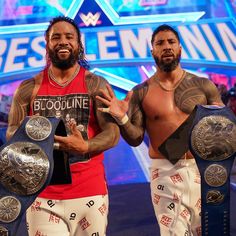 two men standing next to each other holding up their wrestling belts