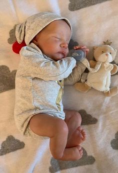 a baby laying on top of a blanket next to a stuffed animal