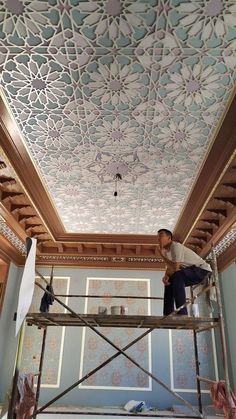 a man on a scaffold working on a ceiling