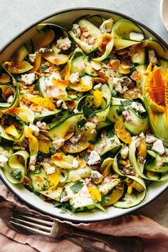 a bowl filled with zucchini, cheese and other food on top of a table