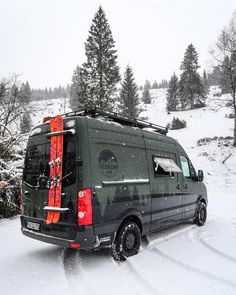 a van is parked in the snow with skis on it's back end