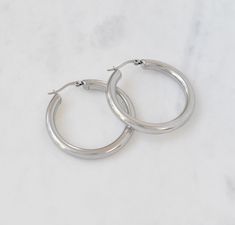 "SILVER MEDIUM CHUNKY HOLLOW HOOP EARRINGS Extremely lightweight, but oh so durable! These chunky silver hoops are a must have staple! Polished to perfection, these hoops will immediately add chicness to your look, day or night! Also available in gold Materials: Stainless steel Measurements: Outer diameter 1.625\", inner diameter 1.188\" . Hoop thickness 4mm Closure: Latch back Additional Info:  Hypoallergenic High Polish Eco-friendly: We use sustainable metals Tarnish resistant and waterproof" Aesthetic Earrings Silver, Silver Hoops Aesthetic, Silver Earrings Aesthetic, Hoop Earrings Aesthetic, Celine Earrings, Thick Hoop Earrings, Earrings Aesthetic, Concert Fits, Prom Jewelry