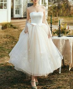 a woman in a white dress standing next to a table