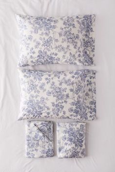 the blue and white bedding is laid out on top of each other with matching pillows