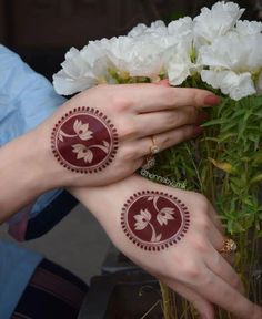 two hands with henna tattoos on their palms and white flowers in front of them