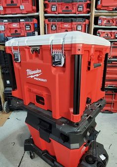 a large red tool box sitting on top of a dolly in a room filled with boxes