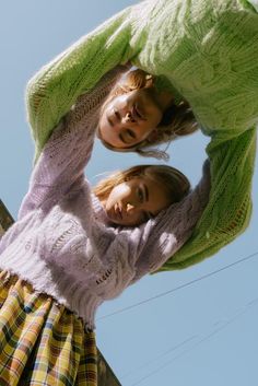 two young women standing next to each other in front of a blue sky and telephone pole