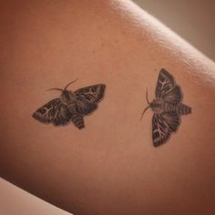 two small butterflies on the back of a woman's shoulder, one is black and white