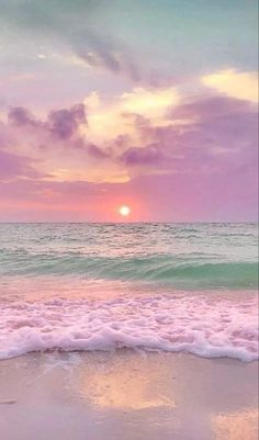 the sun is setting over the ocean with waves coming in to shore and pink clouds