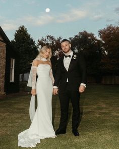 a man and woman in formal wear standing next to each other on the grass outside