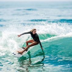 a woman riding a wave on top of a surfboard