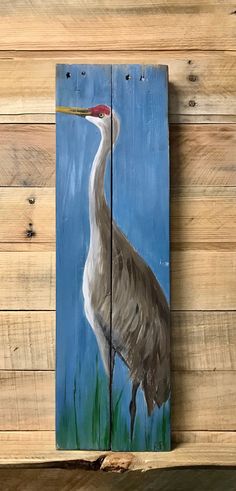 a painting of a crane is on a wooden paneled wall next to wood planks