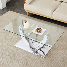 a glass table sitting on top of a carpeted floor next to a white couch