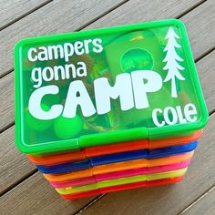 a stack of colorful plastic cups sitting on top of a wooden table next to a green container