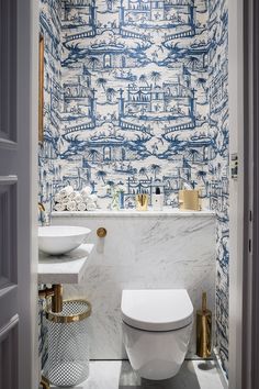 a white toilet sitting next to a sink in a bathroom under a blue and white wall