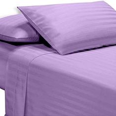 a bed with purple sheets and pillows on it