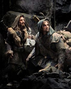 two men dressed in medieval clothing sitting on rocks