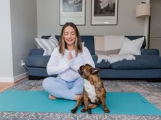 a woman sitting on a yoga mat with her dog