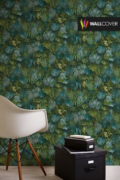 a white chair sitting in front of a wallpapered with green leaves on it