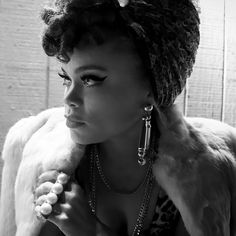 a woman in a fur coat and some pearls on her necklaces is looking away from the camera