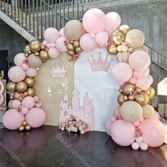 a table topped with balloons and a castle shaped frame filled with pink, gold and white balloons