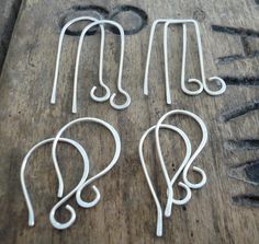 four pairs of ear hooks sitting on top of a wooden table next to some scissors