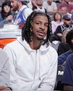 a man with dreadlocks sitting in front of a crowd