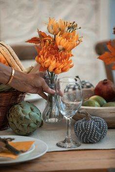 a person placing flowers in a vase on top of a table with other food items