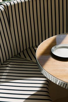 a plate sitting on top of a wooden table next to a striped chair with black and white stripes