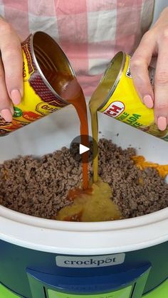 a person pouring sauce into a crock pot filled with ground beef and other ingredients