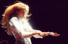 a woman with long red hair is holding something in her hand while standing on stage