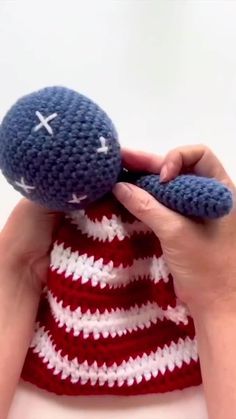 a hand holding a crocheted stuffed animal in the shape of an american flag