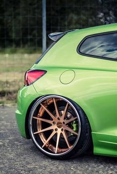 the rear end of a green car with gold rims