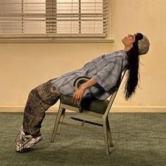 a woman laying on top of a chair with her eyes closed and head tilted to the side