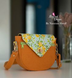 an orange purse sitting on top of a table next to a vase filled with flowers