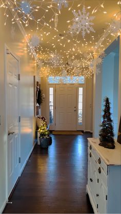 a hallway decorated for christmas with lights and decorations hanging from the ceiling, along with an entry door