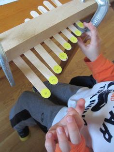 a child playing with a musical instrument made out of wooden pegs and plastic picks