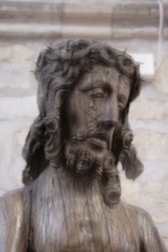 a close up of a statue of jesus with his head turned to the side and hair blowing in the wind