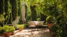 an outdoor patio with tables and chairs surrounded by greenery