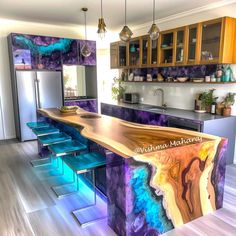 an island in the middle of a kitchen with blue stools and wooden counter tops