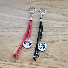 two keychains with mickey mouse charms attached to them on a wooden table top