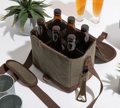 a bag filled with beer bottles sitting on top of a table next to two glasses