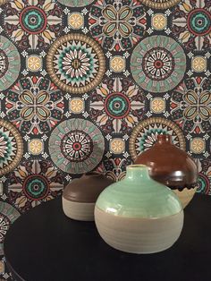 two vases sitting on top of a table next to a wallpapered wall